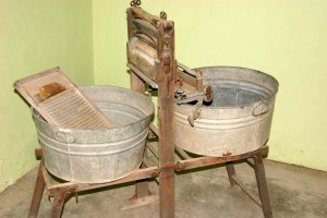 A soapy tub and washboard (on left),a ringer in middle, and a rinse tub on the right.